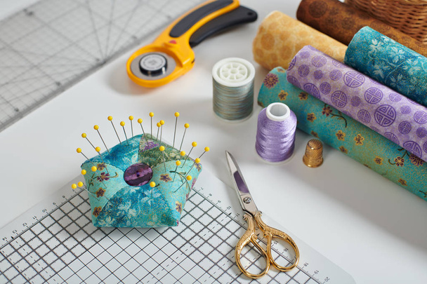 Pincushion, craft mat, scissors, rotary cutter, fabric rolls, sewing and quilting accessories - Photo, Image