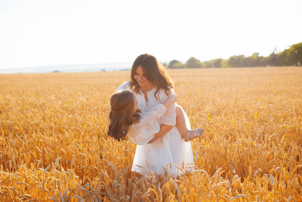 Фотографія матері, яка розважається в полі зі своєю донькою, вдягнена
 - Фото, зображення