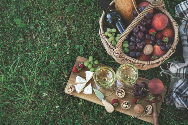 Picnic setting with  two glasses of white wine,  cheese, fruits  - Photo, image