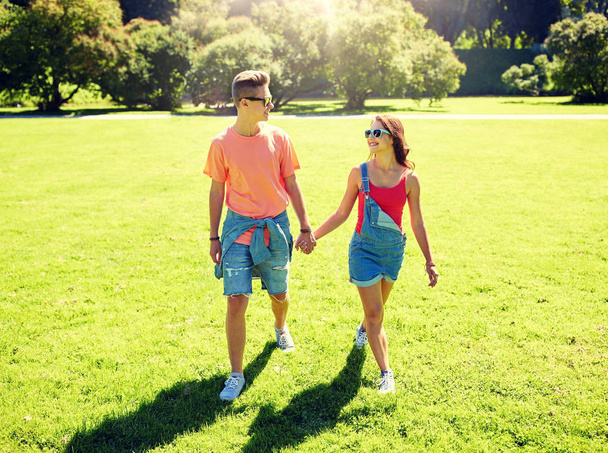 happy teenage couple walking at summer park - Fotó, kép