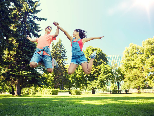 happy teenage couple jumping at summer park - Zdjęcie, obraz