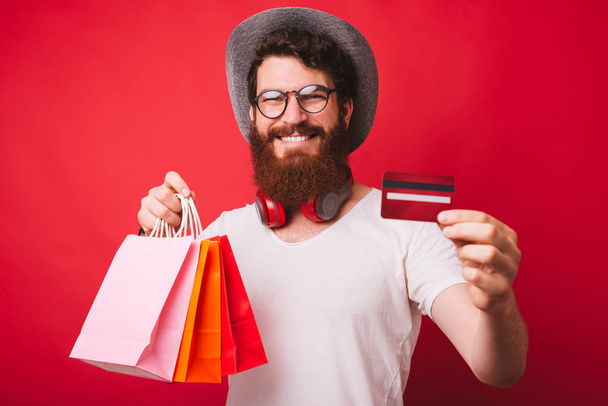 Shopaholic Man, κρατώντας μερικές σακούλες, και δείχνοντας πιστωτική κάρτα στο Ca - Φωτογραφία, εικόνα