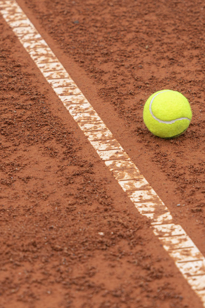 Piłka tenisowa leżąca w pobliżu białej linii na tle kortu tenisowego - Zdjęcie, obraz