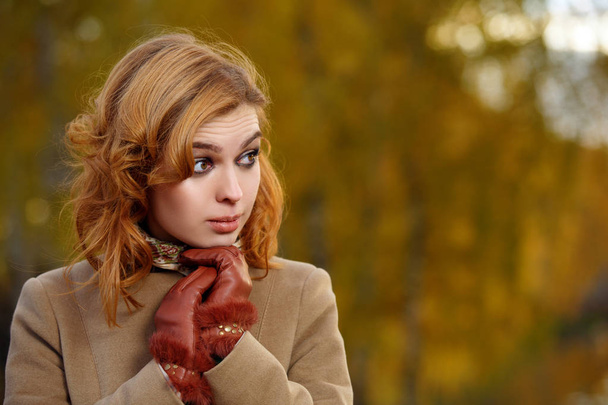 Stílusos nő bézs kabátot és kesztyűt álló őszi sárga parkban. - Fotó, kép
