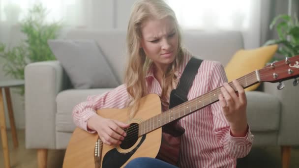 Beautiful woman playing guitar in his living room - Кадри, відео