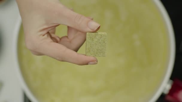 mouvement lent de la main féminine jetant cube épicé dans le bouillon
  - Séquence, vidéo
