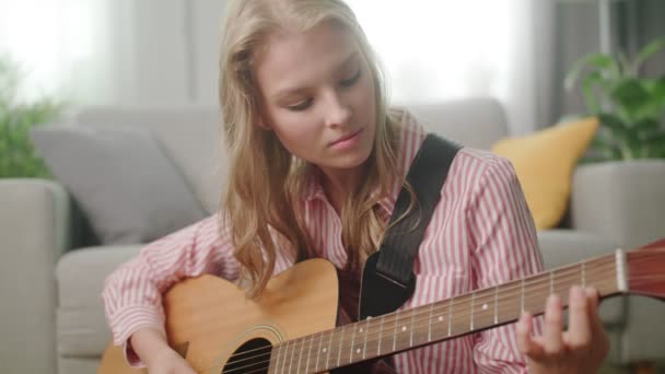 Beautiful woman playing guitar in his living room - Video, Çekim