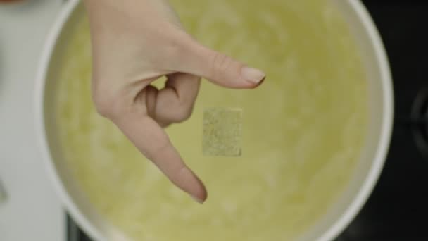 Slow Motion van vrouwelijke hand gooien pittige kubus in Bouillon  - Video