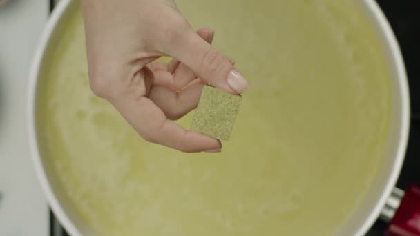 Slow Motion van vrouwelijke hand gooien pittige kubus in Bouillon  - Video