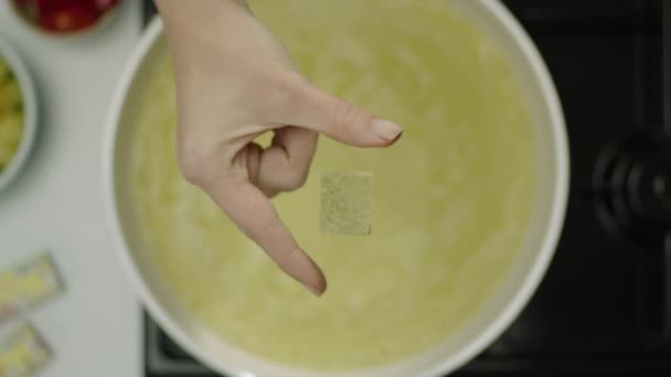 αργή κίνηση των γυναικών χέρι ρίχνοντας πικάντικο κύβο σε ζωμό  - Πλάνα, βίντεο