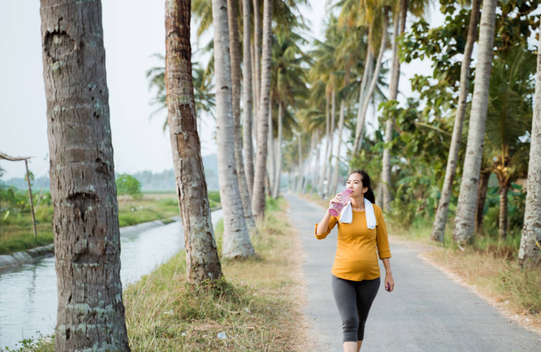 pregnant woman after workout drinking a bottle of water - Foto, imagen