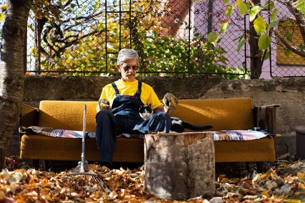 Hombre sentado en el sofá después de limpiar en el patio
 - Foto, Imagen