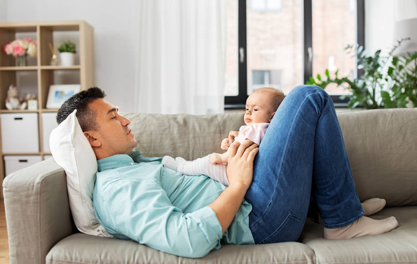 middle aged father with baby lying on sofa at home - Foto, Imagem