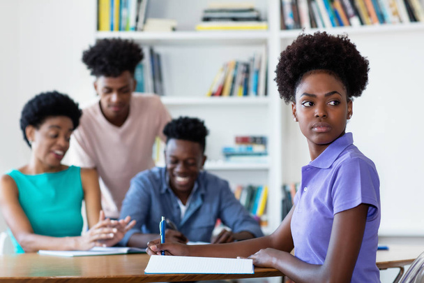 Afrikkalainen amerikkalainen naispuolinen opiskelija opiskelee työpöydällä koulussa
 - Valokuva, kuva