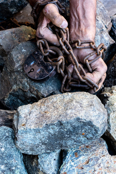 The hands of a slave in an attempt to release. The symbol of slave labor. Hands in chains - Foto, Imagen