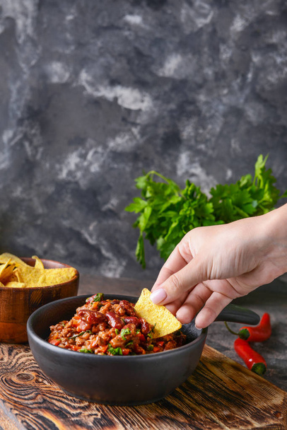 Woman eating tasty chili con carne with nachos - Photo, image