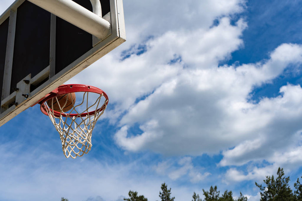 Basketball backboard with a ring on the street and blue sky - Photo, image