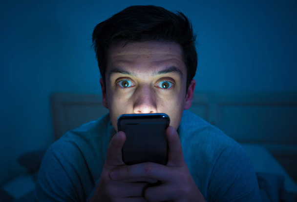 Young mobile phone addict man awake at night in bed using smartphone for chatting, flirting and sending text message. In communication, Internet addiction and Social media network abuse concept - Fotó, kép