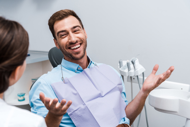 selektivní zaměření šťastného pacienta gestikulovat a dívat se na zubaře  - Fotografie, Obrázek
