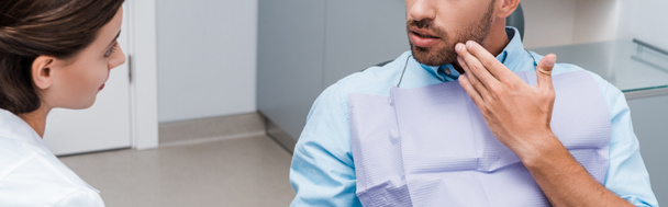 panoramic shot of man gesturing near attractive dentist in clinic  - Фото, зображення