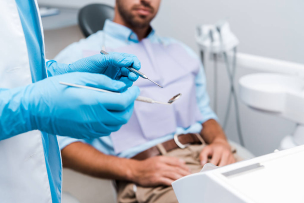 enfoque selectivo del dentista en guantes de látex azul que sostienen instrumentos dentales cerca del paciente
   - Foto, Imagen