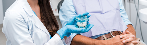 panoráma lövés fogorvos latex kesztyű gazdaság fogak modell beteg közelében összeszedte kézzel  - Fotó, kép