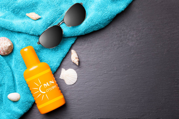 Sun cream with seashells, sunglasses and towel. - Foto, afbeelding