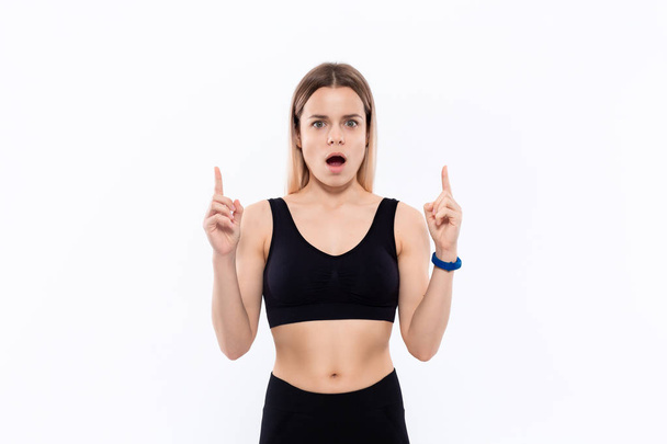 Young sporty blond woman in a black sportswear looking at smart watches checking pulse after workout standing over white background. - Photo, Image