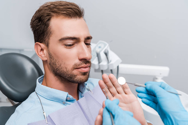 nyírt a fogorvos a latex kesztyű gazdaság fogászati eszközök közelében betegnek a klinikán  - Fotó, kép