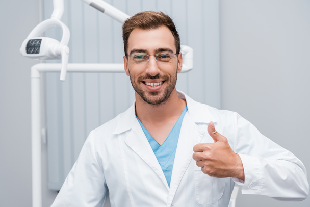 Glücklicher Arzt mit Brille zeigt Daumen nach oben in Klinik  - Foto, Bild