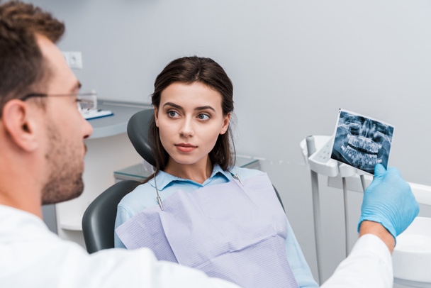 selective focus of attractive woman looking at dentist with x-ray  - Photo, Image