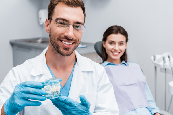 вибірковий фокус щасливого бородатого стоматолога, який тримає модель зубів біля щасливої дівчини
  - Фото, зображення