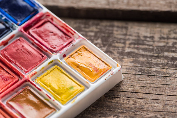 close up view of watercolor colorful paint palette on wooden table - Zdjęcie, obraz