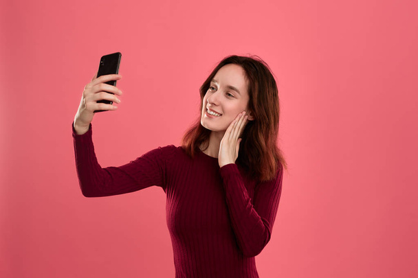 Foto van een mooie jonge brunette vrouw maken selfie met een mobiele telefoon. - Foto, afbeelding