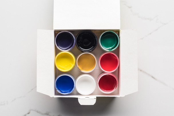 top view of colorful gouache paints in box on marble surface - 写真・画像