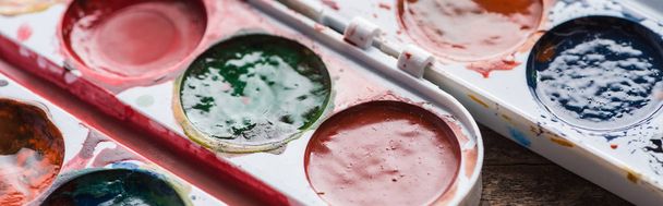 close up view of watercolor paint palettes on wooden table, panoramic shot - Фото, зображення
