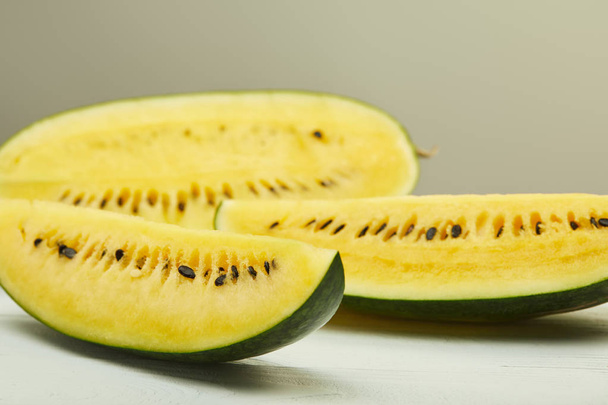 ripe yellow watermelon with seeds on white wooden table isolated on grey - Foto, Imagem
