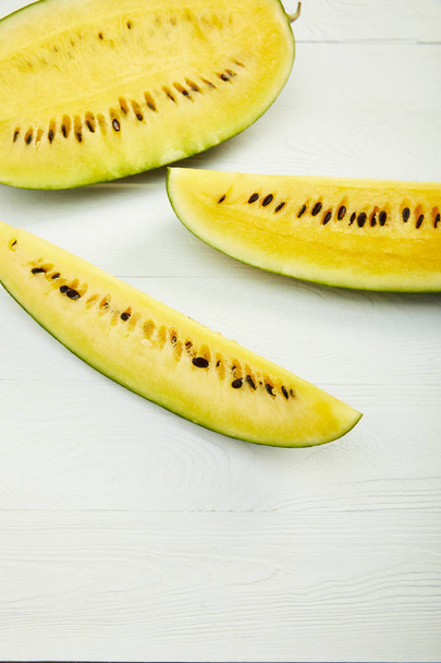 ripe yellow tasty watermelon with seeds on white wooden table with copy space - Photo, Image