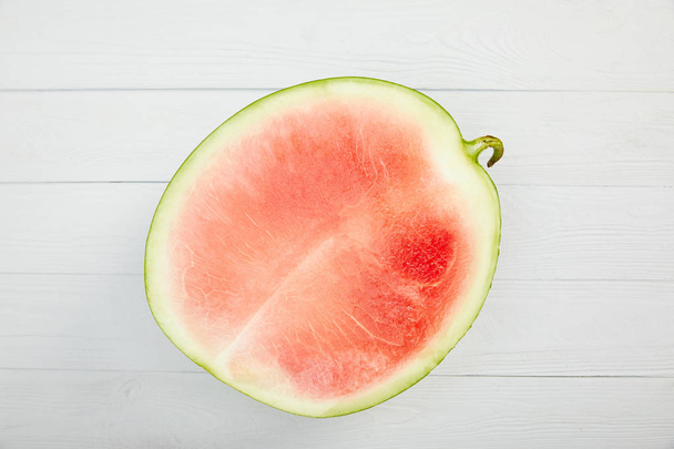 top view of ripe red watermelon half on wooden white table - Fotó, kép