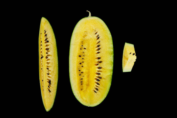 Κορυφαία θέα του λαχταριστά ώριμα κίτρινα κομμένα καρπούζι με σπόρους που απομονώνονται σε μαύρο - Φωτογραφία, εικόνα