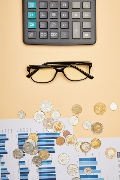 top view of papers, calculator, coins and glasses on table  - Foto, Bild