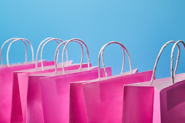 few pink paper shopping bags on blue background  - Photo, Image