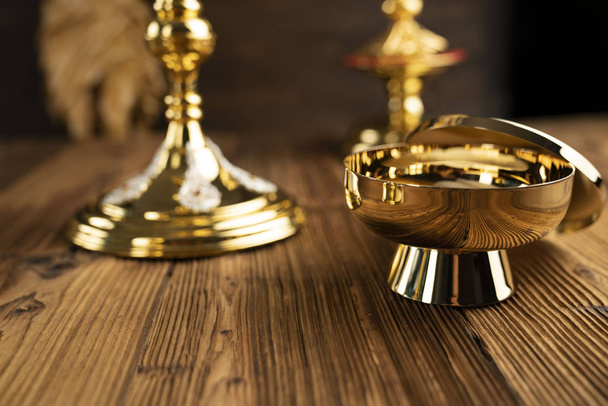 The Cross, monstrance, golden chalice and Bible on the wooden altar. - Valokuva, kuva