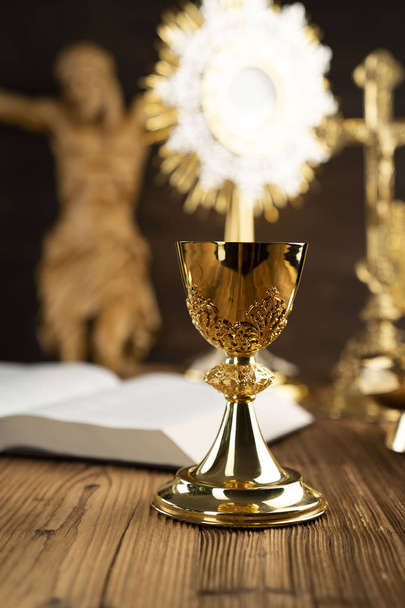 La cruz, la monstrancia, el cáliz de oro y la Biblia en el altar de madera
. - Foto, imagen