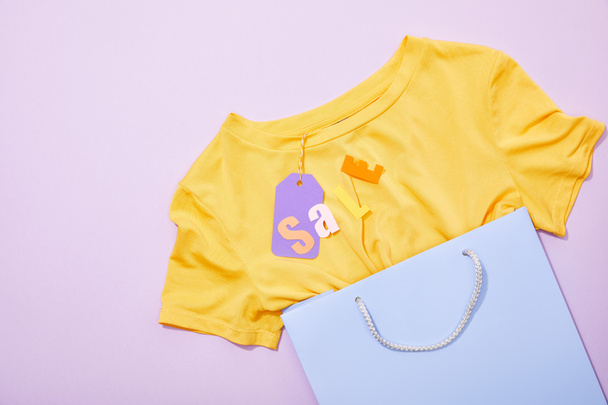 Top kilátás eladó felirat sárga póló lila papír címke bevásárló zsák ibolya  - Fotó, kép
