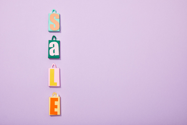 flat lay with colorful shopping bags with sale lettering on violet  - Fotografie, Obrázek