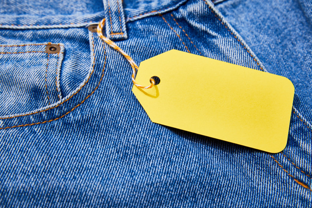 close up view of yellow paper sale tag on rope on jeans  - Foto, Imagem