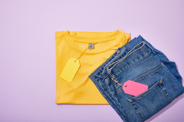 top view of colorful sale tags on t-shirt and jeans on violet  - Fotoğraf, Görsel