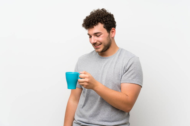 Uomo con i capelli ricci oltre parete isolata in possesso di tazza calda di caffè
 - Foto, immagini