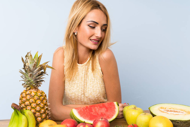 Nuori blondi nainen, jolla on paljon hedelmiä
 - Valokuva, kuva